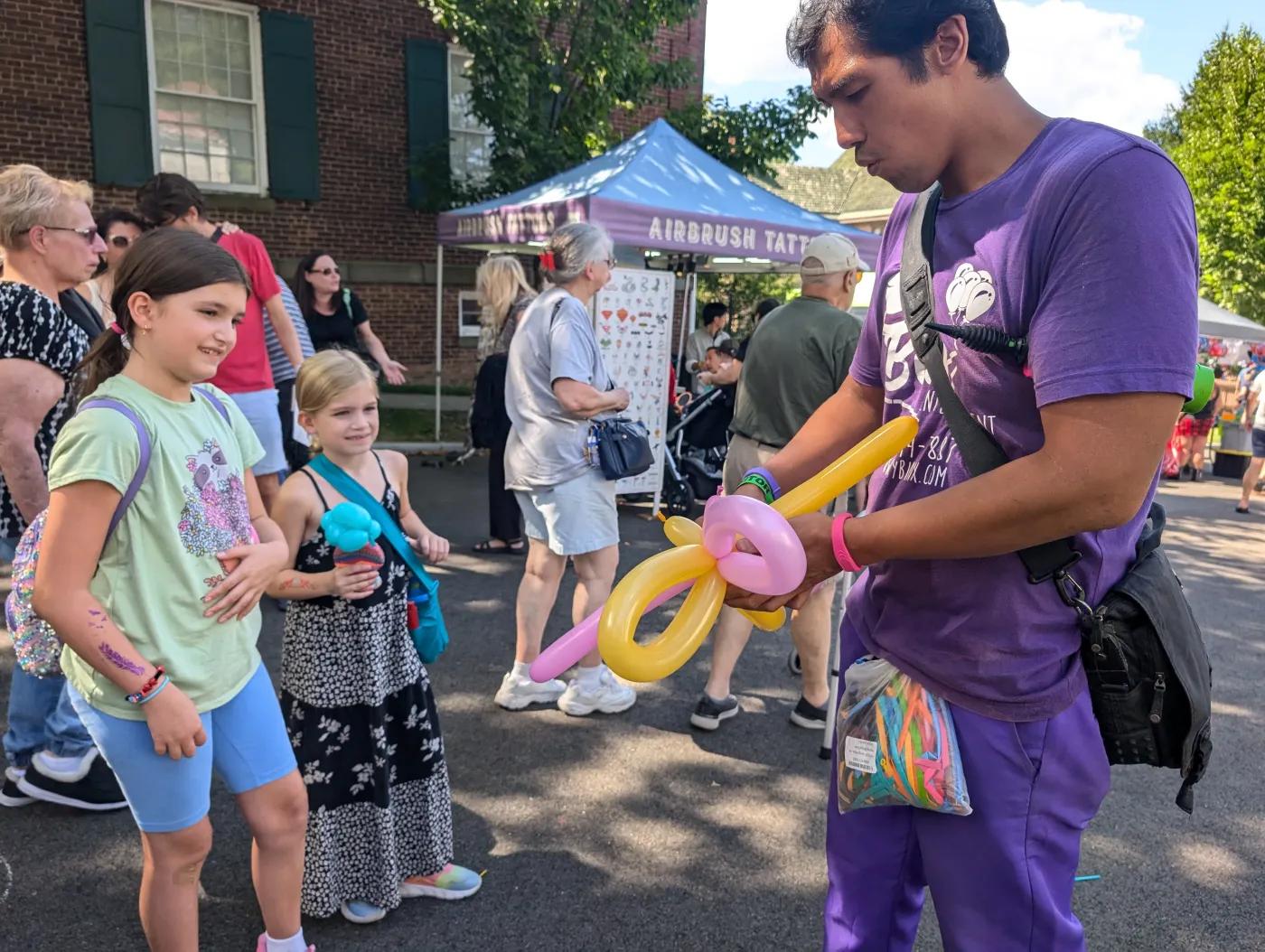 A performer twisting balloons for children outside