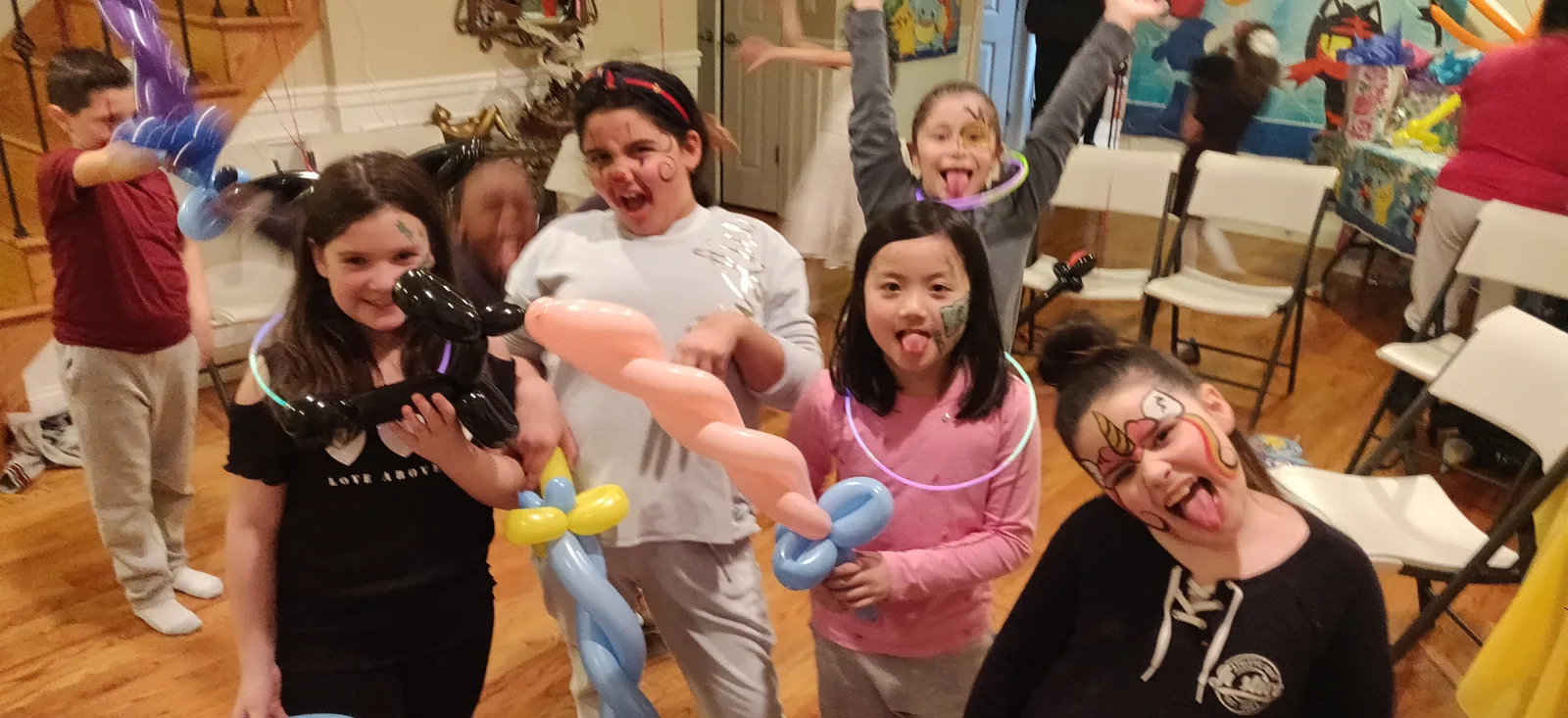 Children and adults holding colorful balloon sculptures indoors