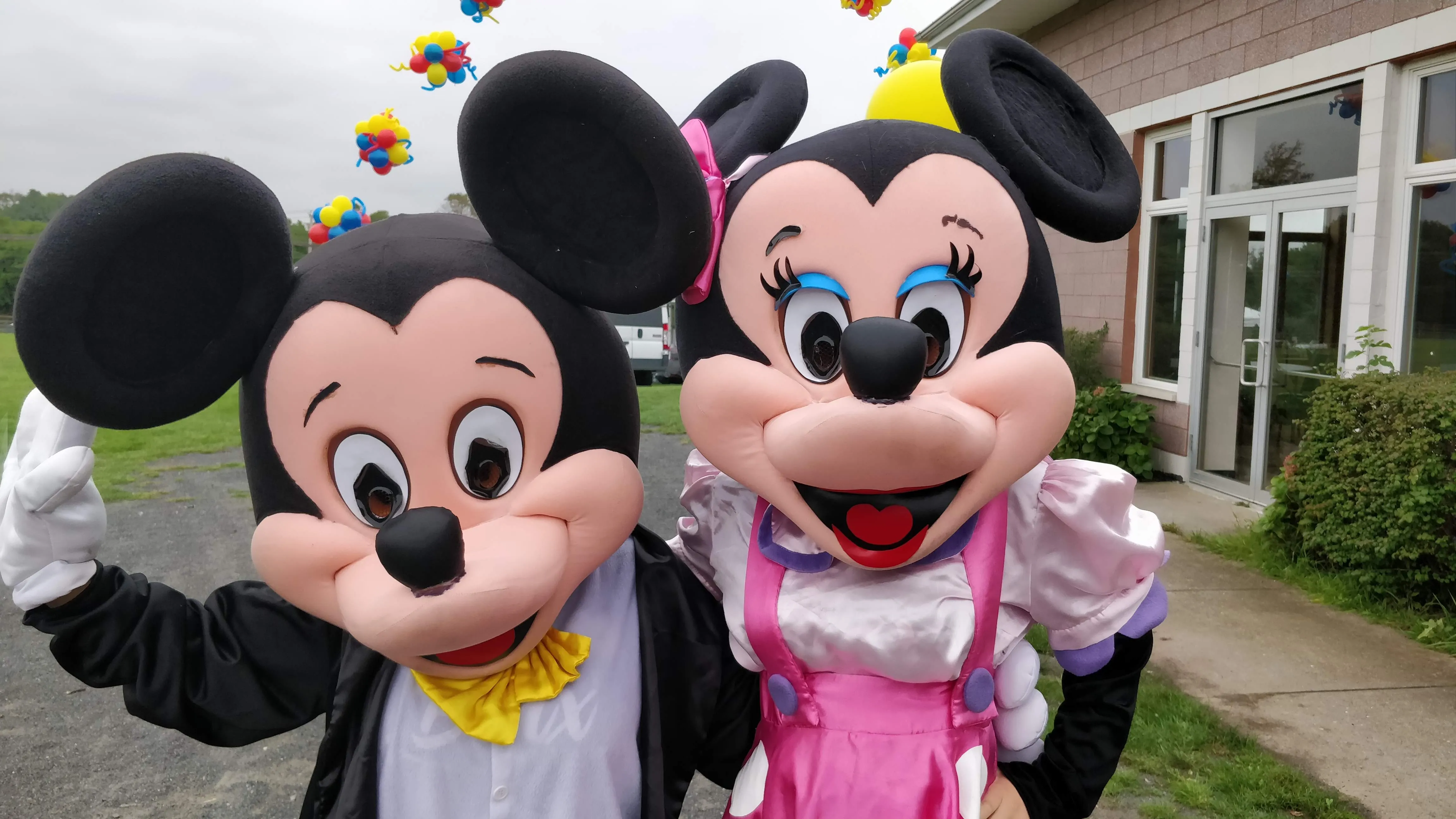 Two mascot characters greeting a child at an outdoor party