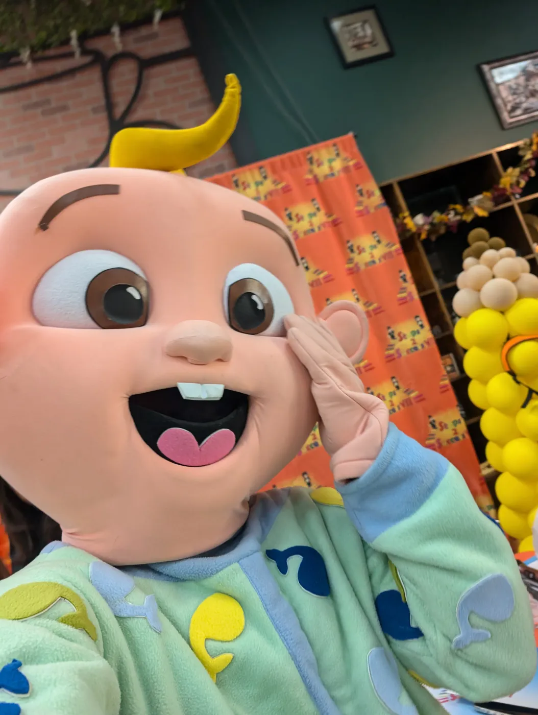 A smiling baby mascot at an indoor celebration