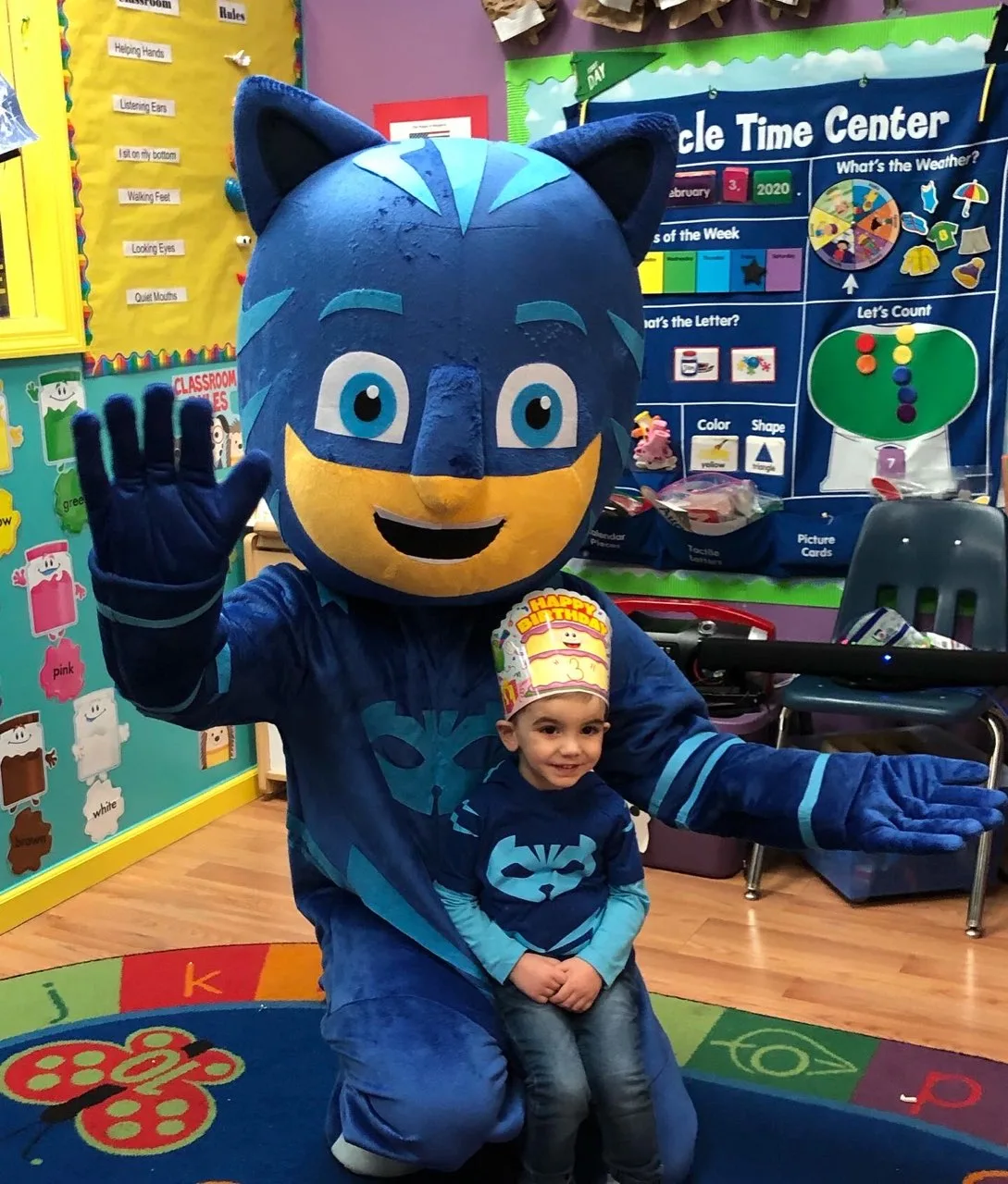 A blue cat mascot posing beside a child