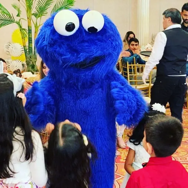 A blue furry mascot greeting guests indoors