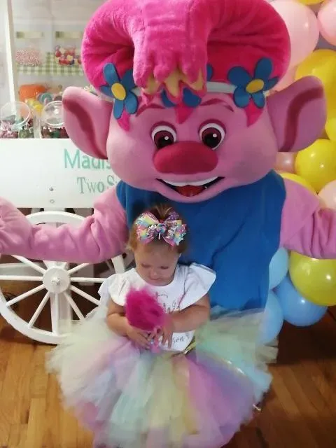 A pink-haired mascot posing beside a child