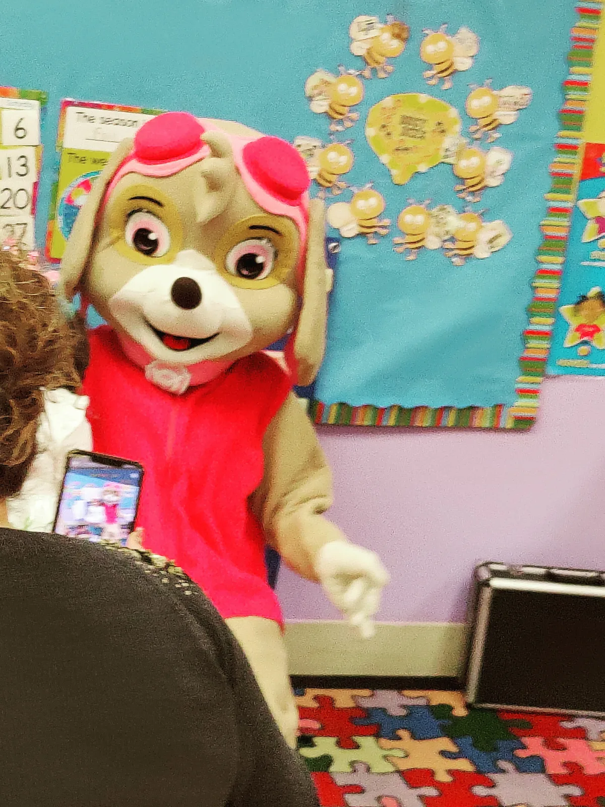 A puppy mascot in pink visiting a classroom