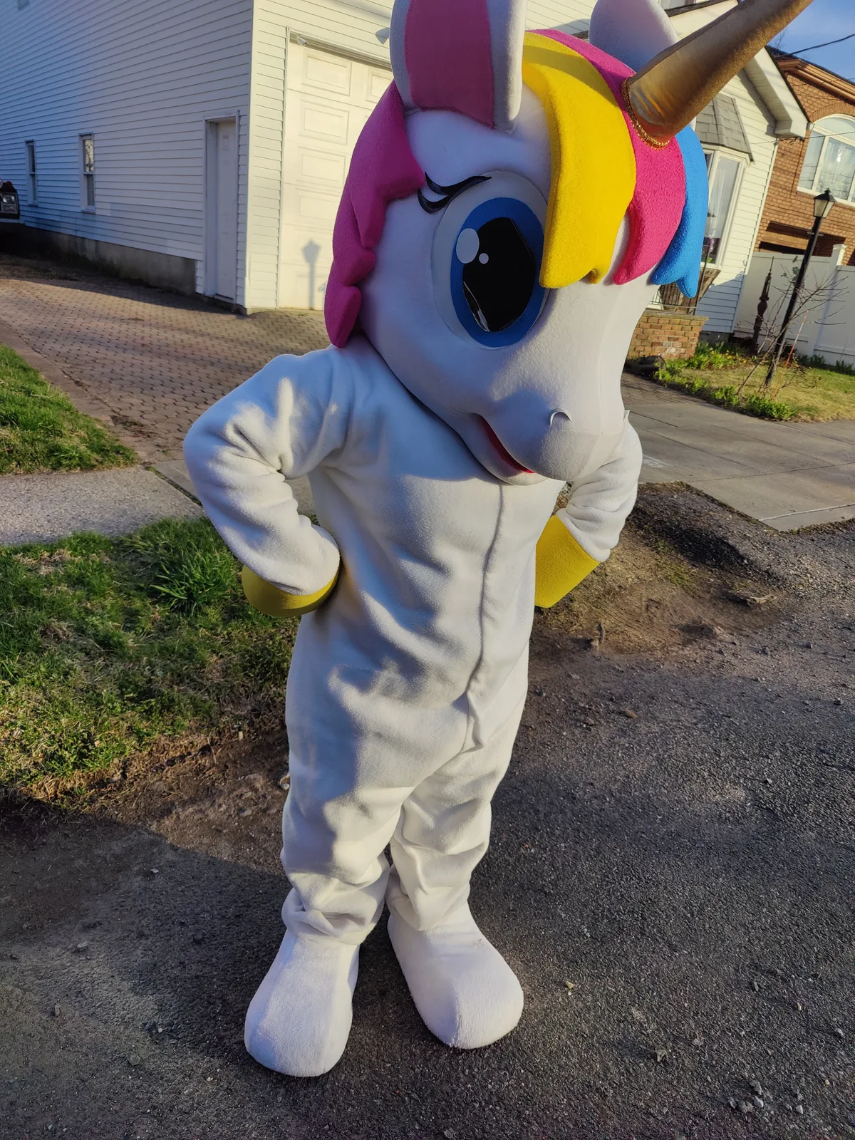 A rainbow pony mascot standing outside a home