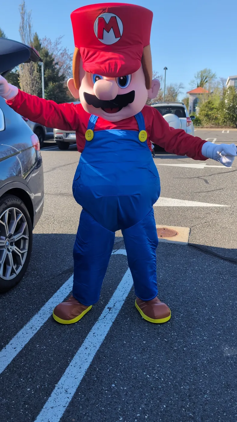 A mascot in a red cap and blue overalls outdoors