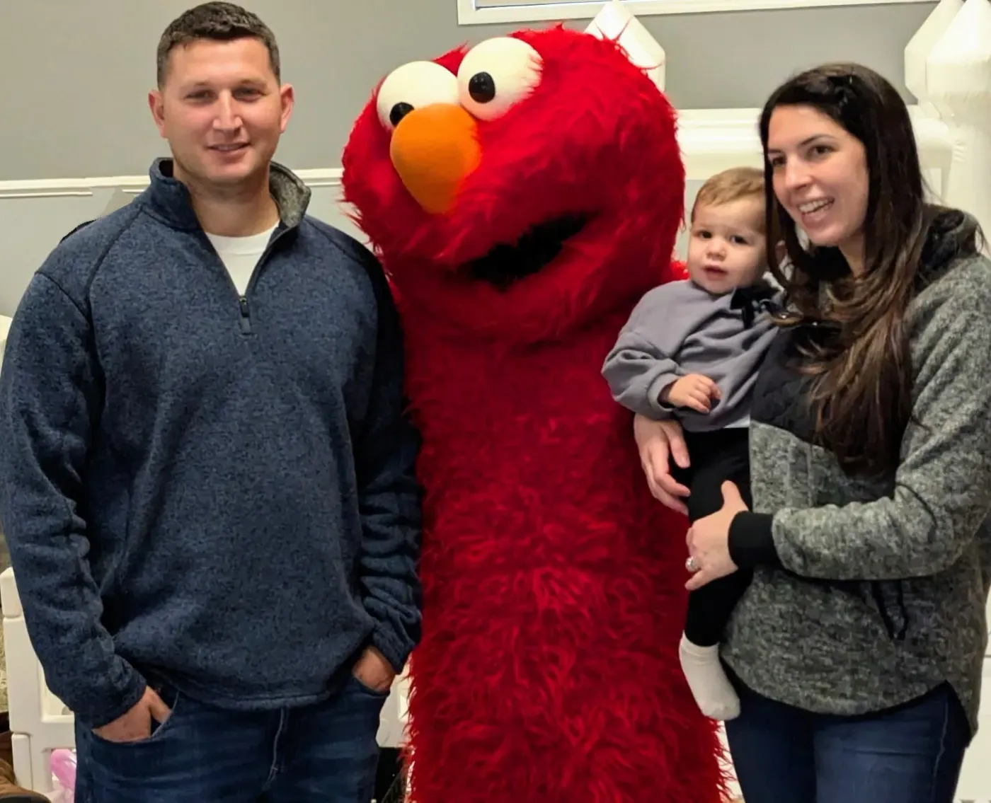 A red furry mascot posing with a family