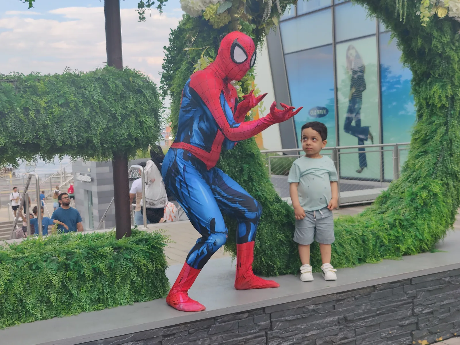 A red and blue superhero performer greeting a child outdoors