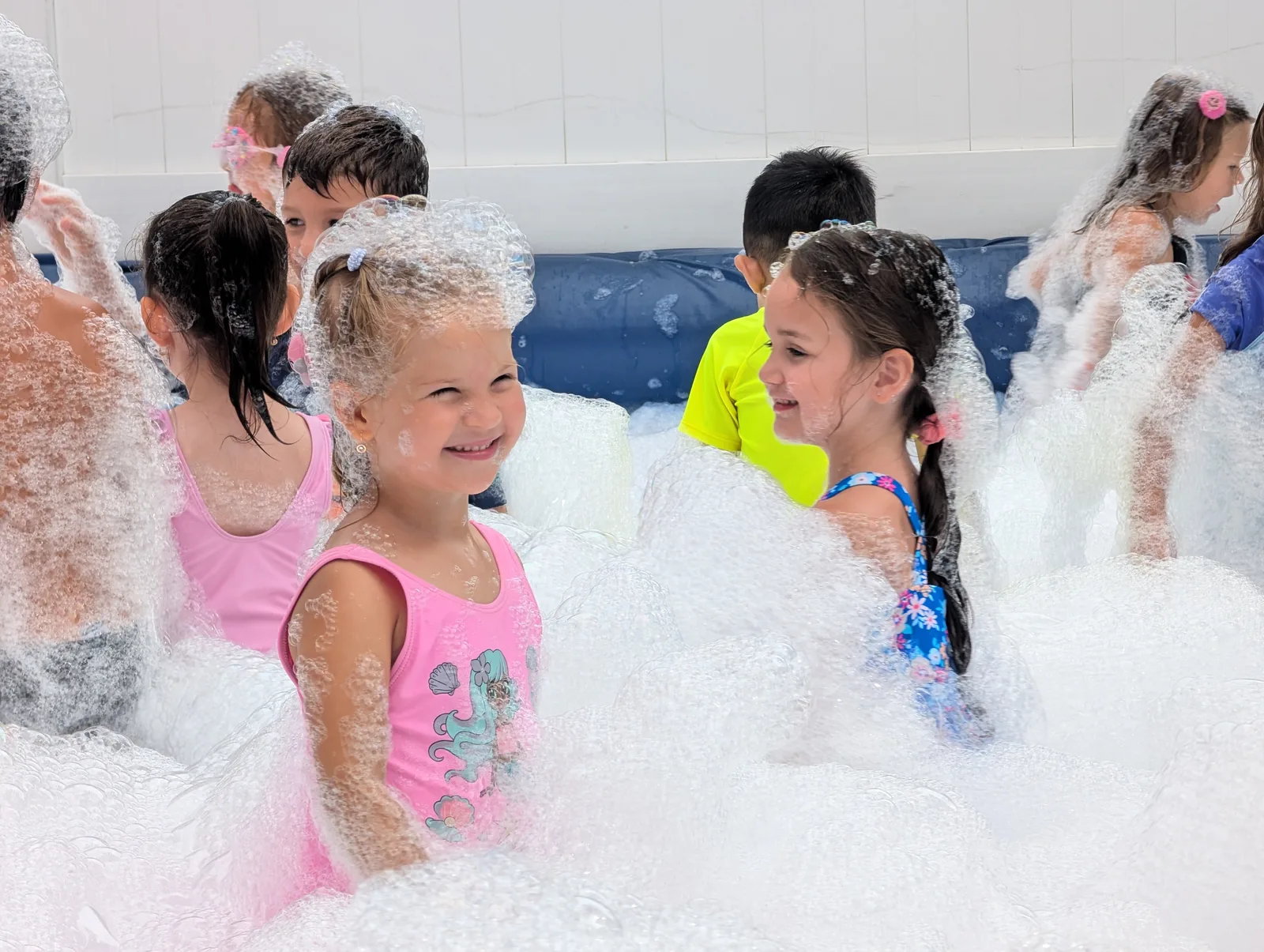 Two children smiling at each other surrounded by foam