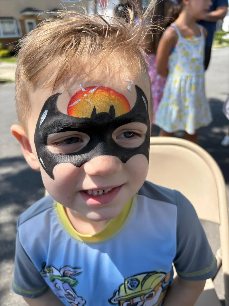 A child's bat-mask face painting with orange details