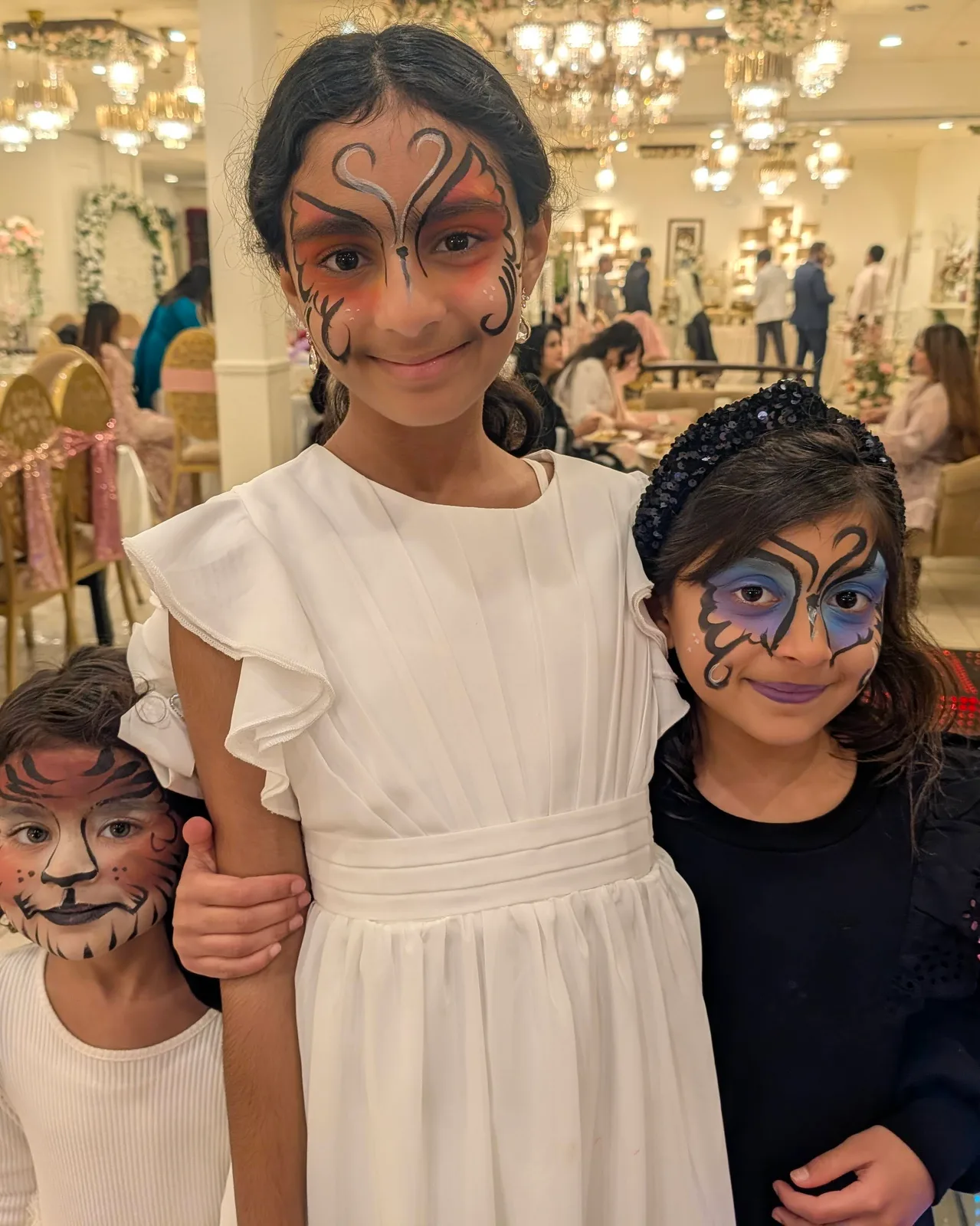 Children posing with colorful designs painted on their faces