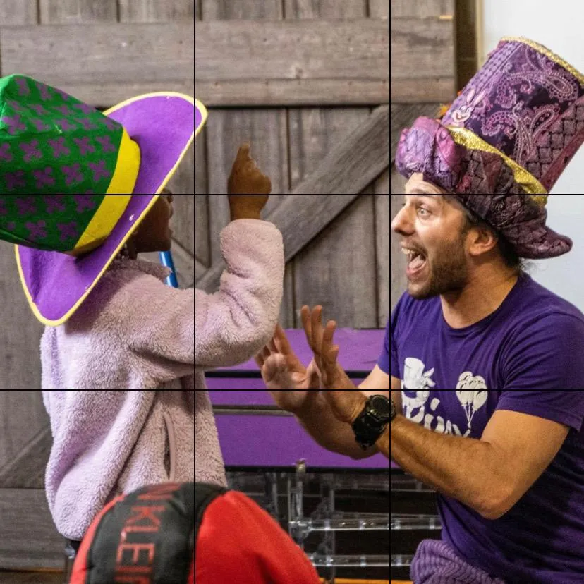 A magician engaging with a child in a colorful hat
