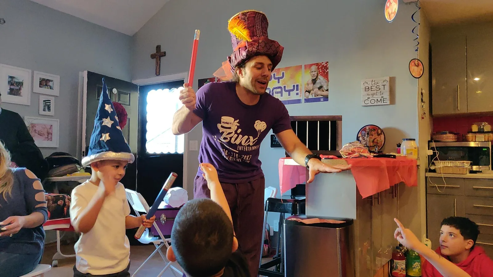 A magician in a purple hat performing for children