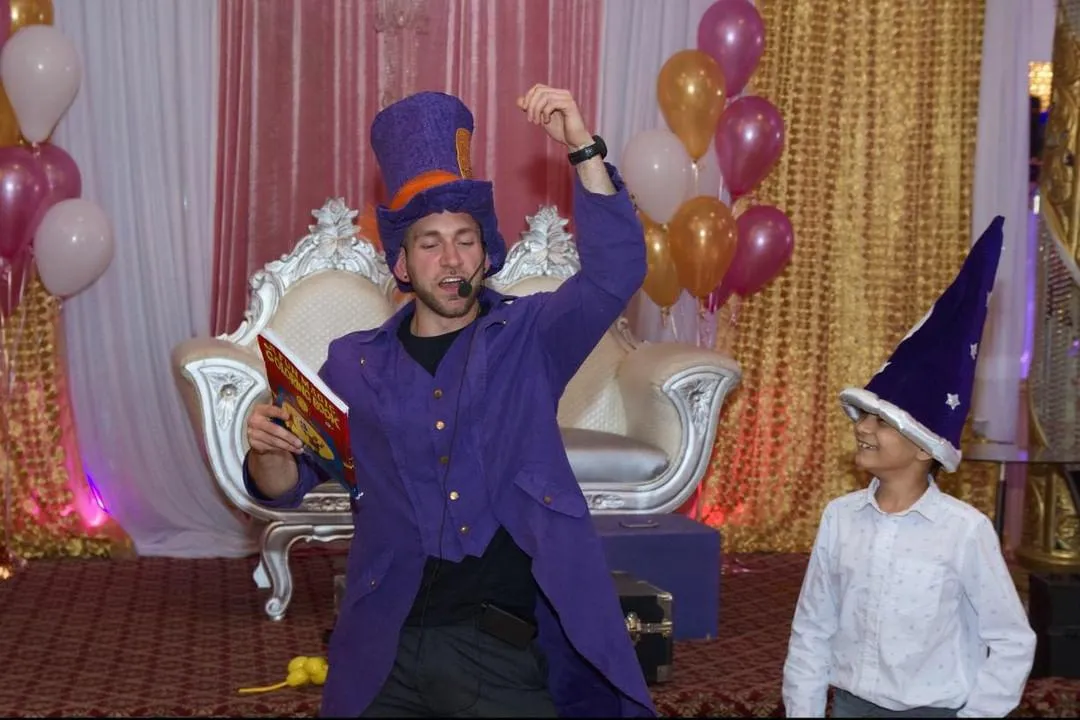 A magician raising both hands during an indoor show