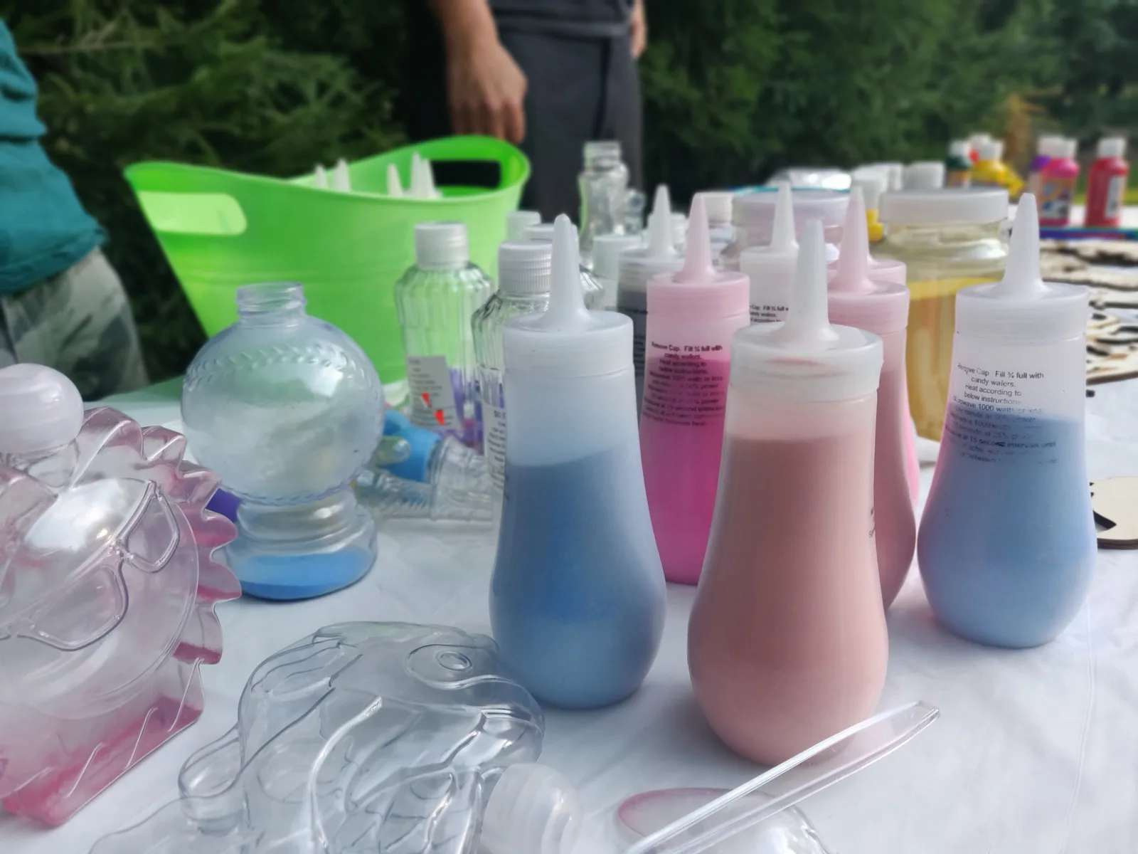 Pink, blue and yellow sand bottles beside clear shaped containers