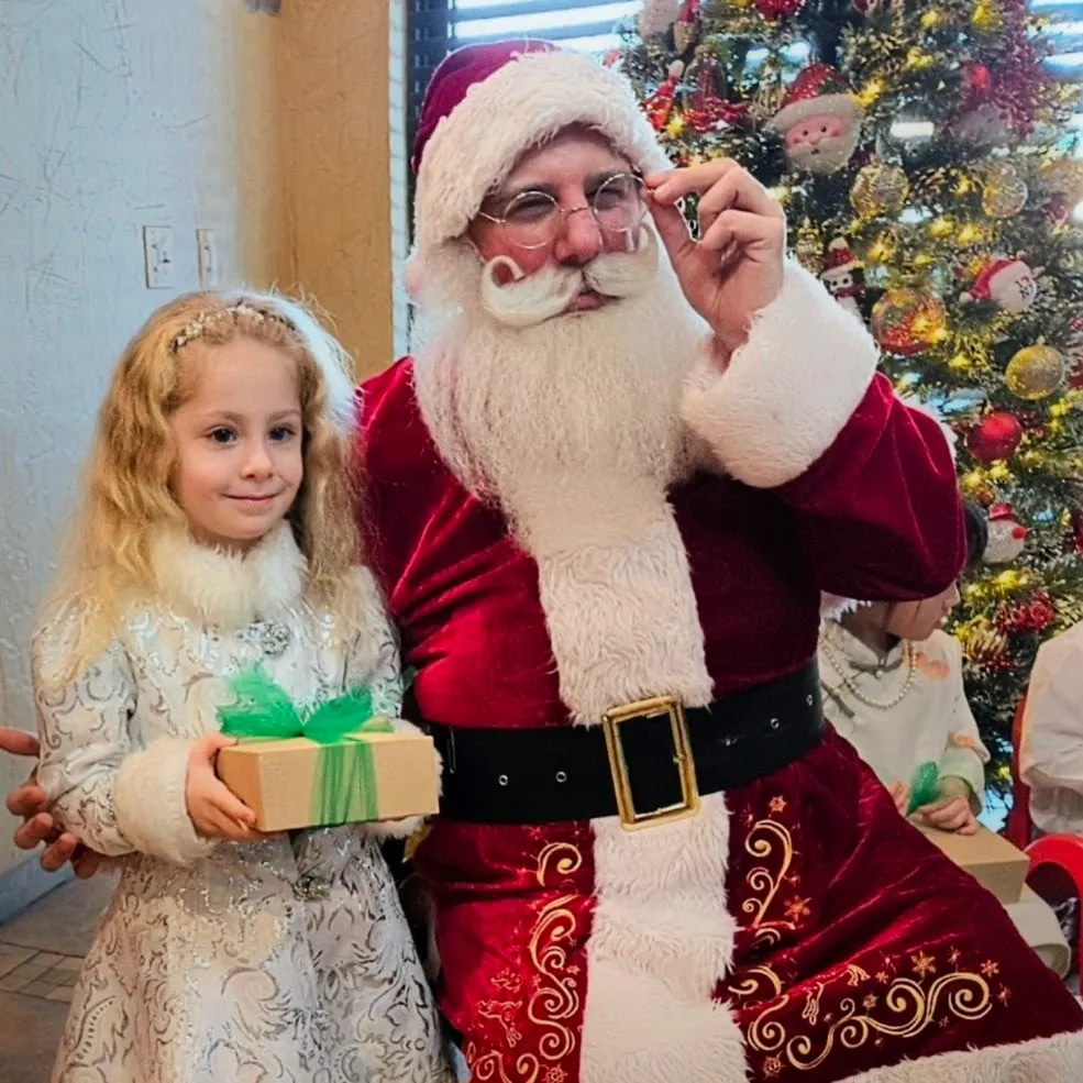 Santa posing with a child holding a gift