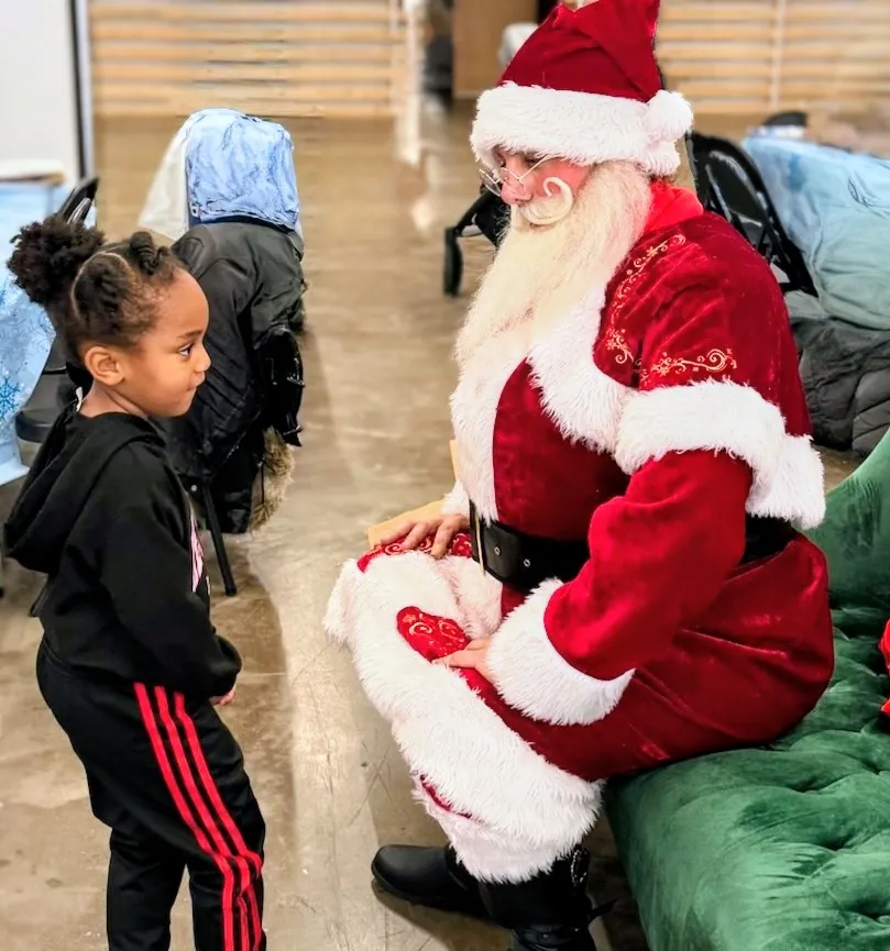 A child speaking with Santa during a visit
