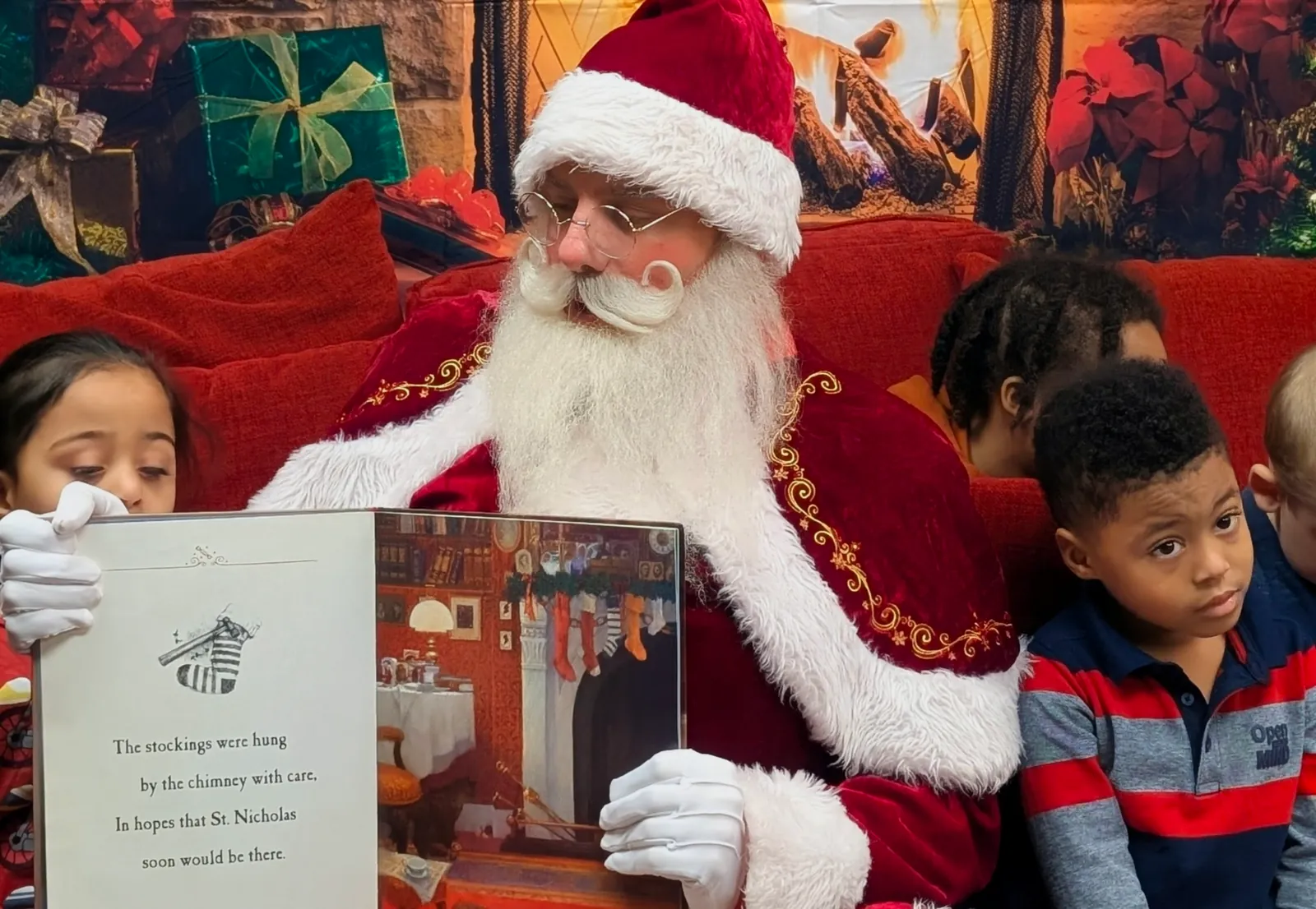 Santa sharing an open storybook with children