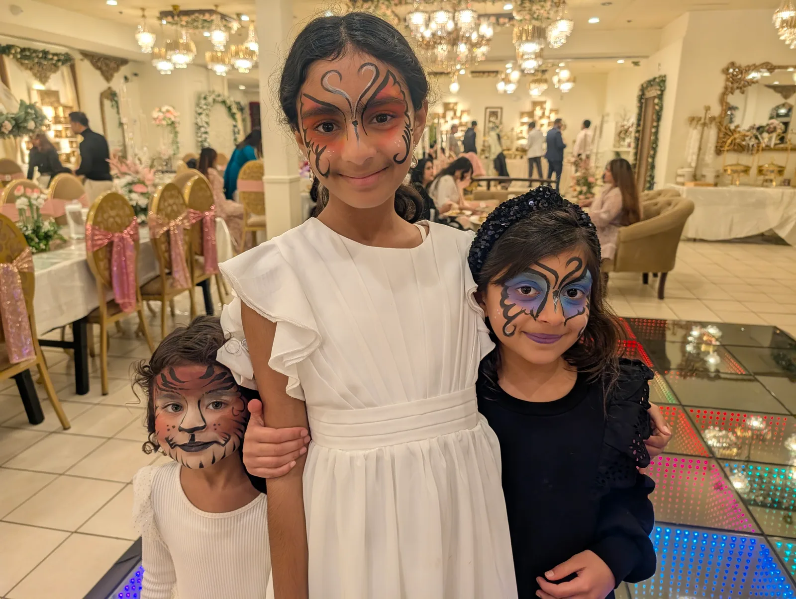Children showing face-paint designs together at a party