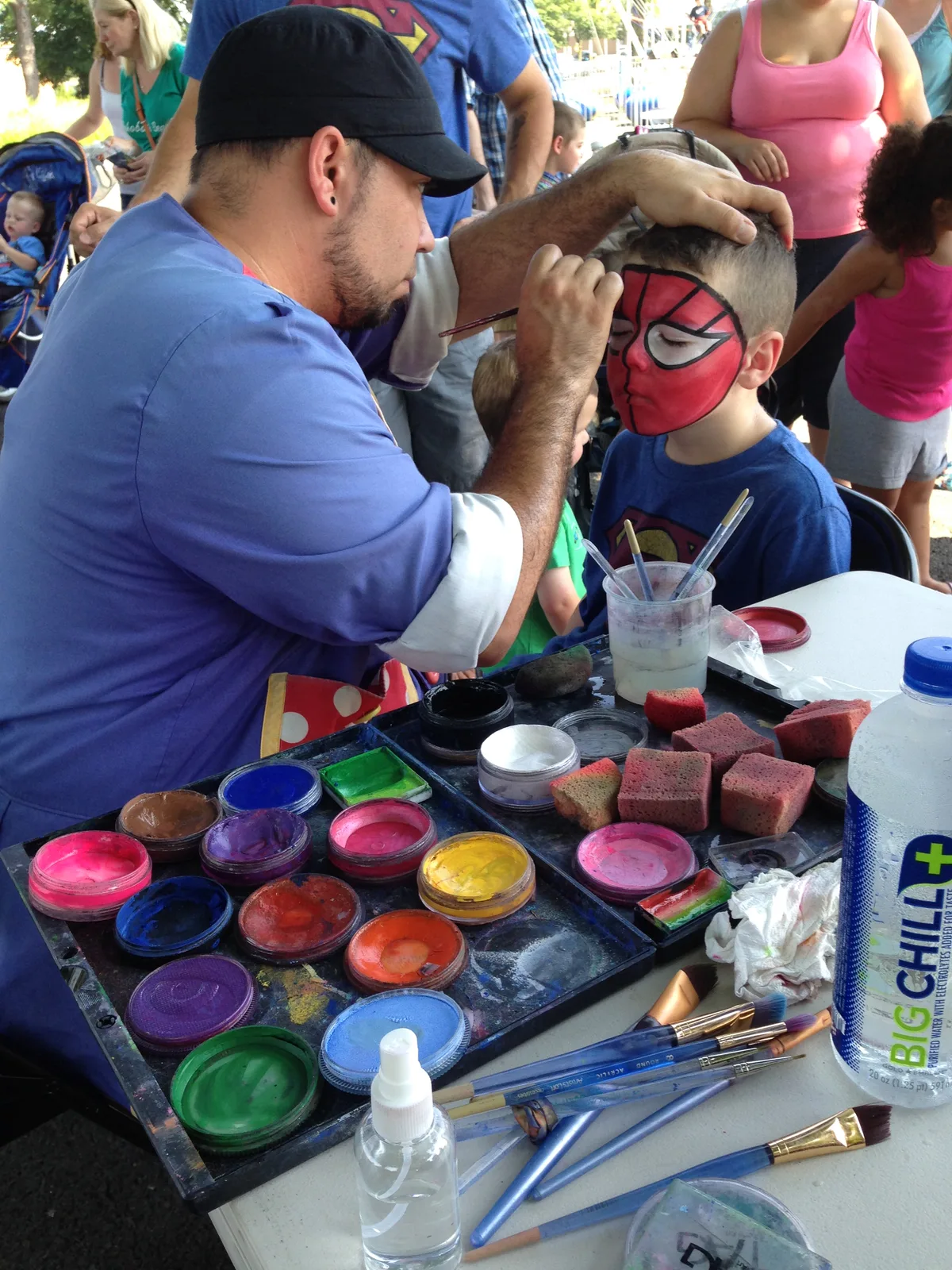 A face painter creating a red and black design for a child
