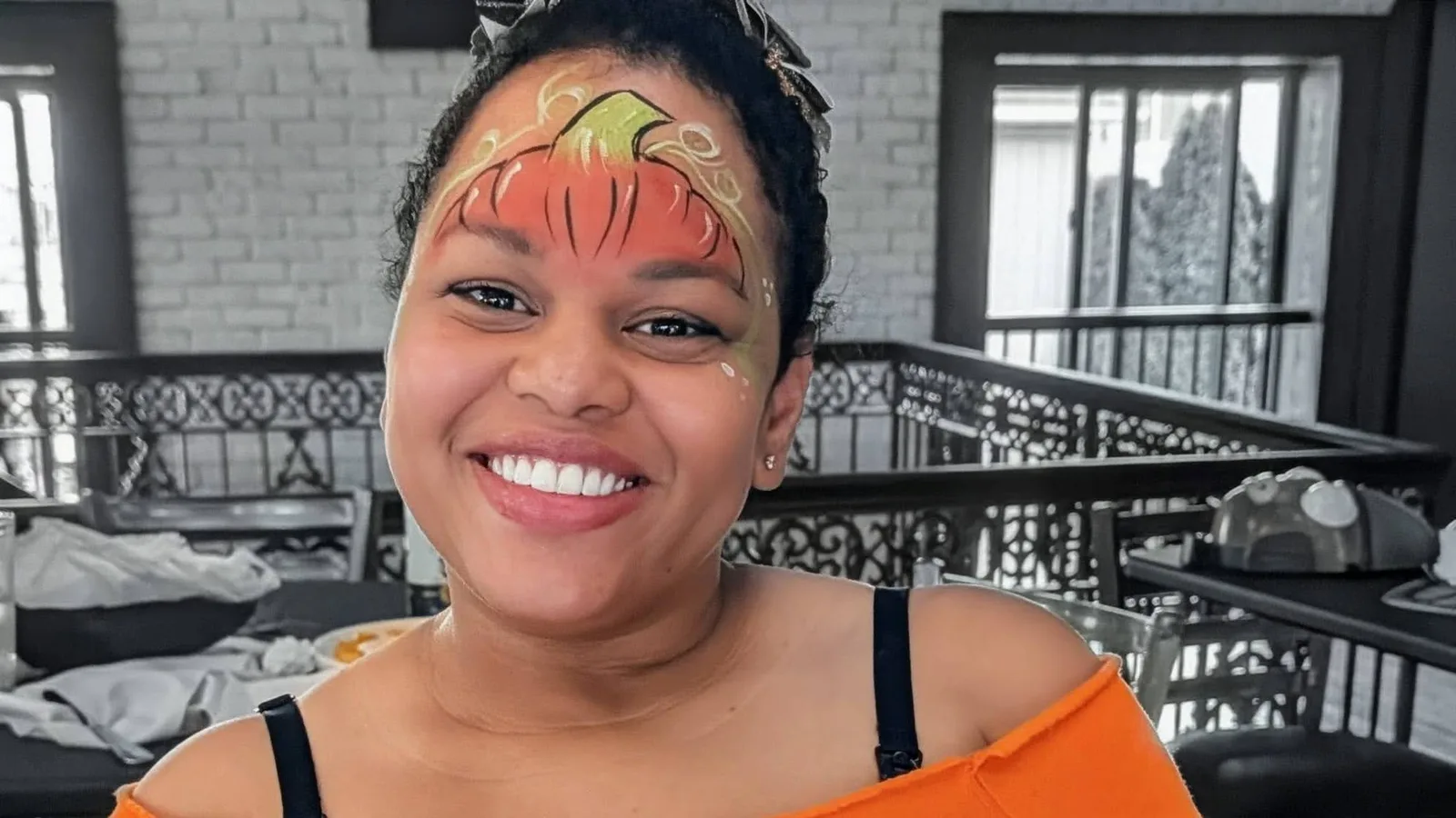Pumpkin face painting with a matching orange Halloween outfit