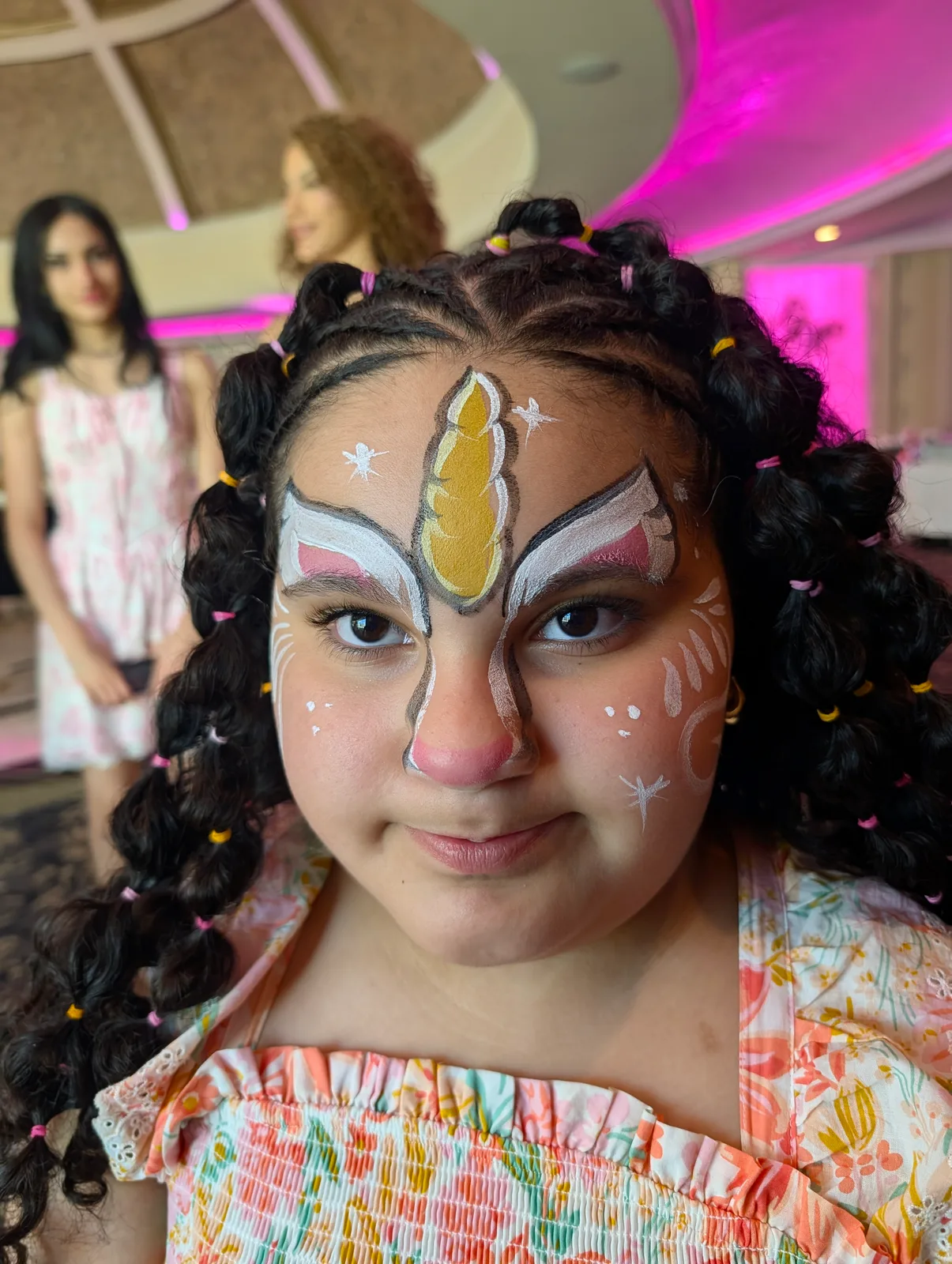 A child with a colorful unicorn design painted on their face