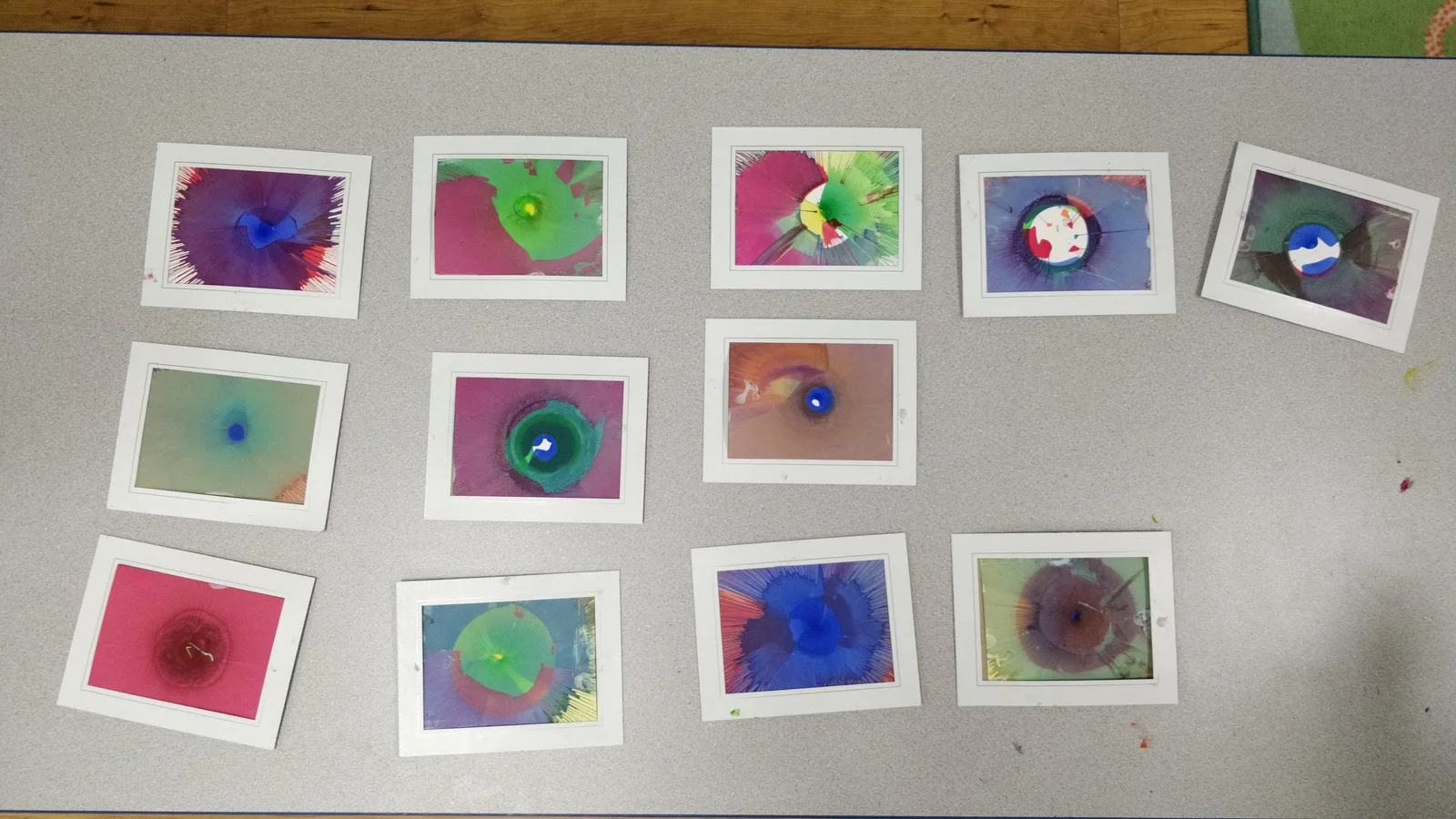 Colorful spin-art cards arranged in white frames on a table